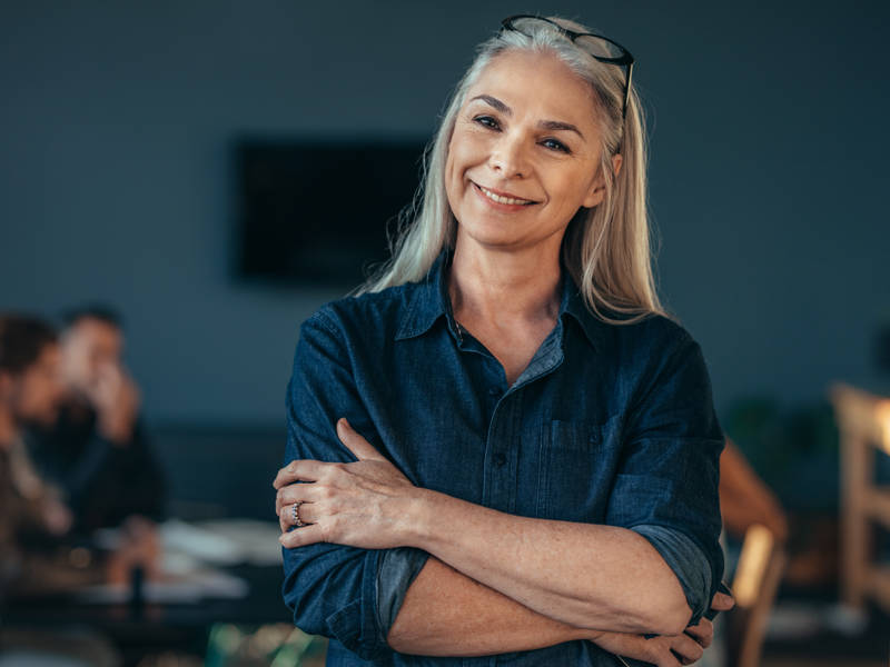 Female employer in blue shirt smiling with arms crossed